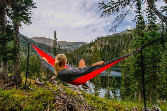 Girl relaxing in a hammock while camping in the woods
